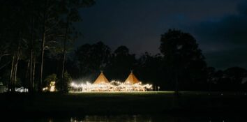 tipi outdoor wedding venue at night with fairy lights on the tents and entryway noosa wedding venue tipi luxe