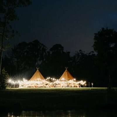 tipi outdoor wedding venue at night with fairy lights on the tents and entryway noosa wedding venue tipi luxe