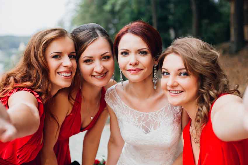 Outdoor portrait of beautiful young bride with her female friends