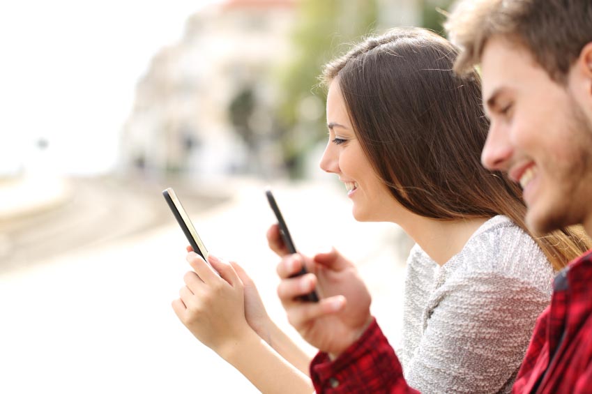 Teen couple using smart phones in a train station