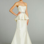 This strapless silk Lexington gown is by Amsale and features an uneven peplum over a pleated taffeta embroidered skirt