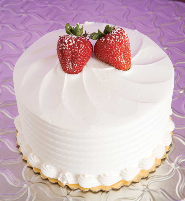 A simple white cake lightly flavored with rum and syrup, this cake is filled with delicious champagne custard and iced with a pale pink whipped topping. It's finished with a shell border and white chocolate curls. Image: Nugget Markets