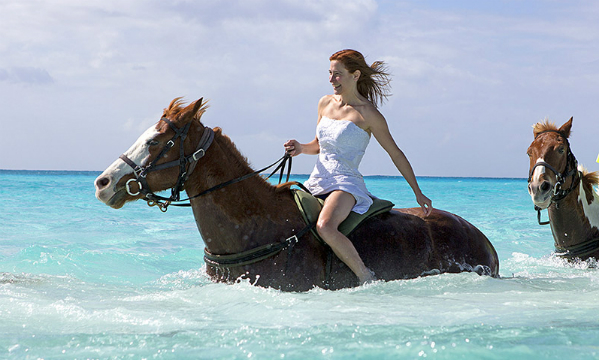 New York bride Jennifer Salvage enjoys a horse ride in Jamaica - in her wedding gown one of 148 places she has worn it. Image: www.OneDressOneWoman.com