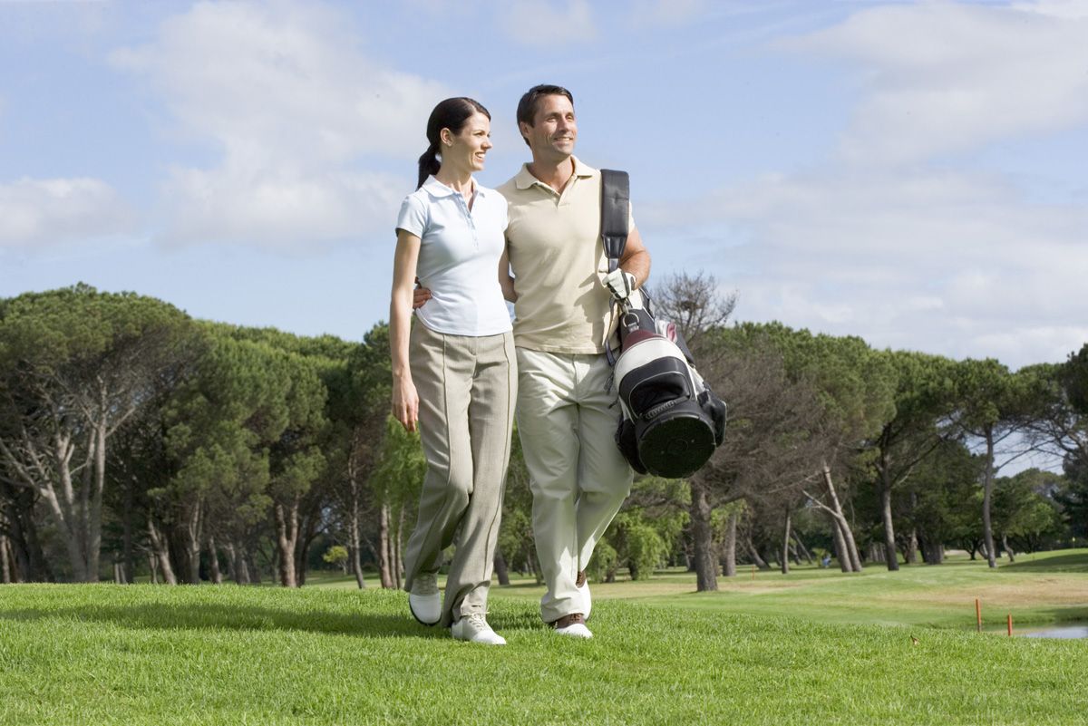 Couple with golf clubs walking on golf course