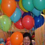The couple's friend smiles among a sea of ballons