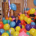The couple's friend smiles among a sea of ballons