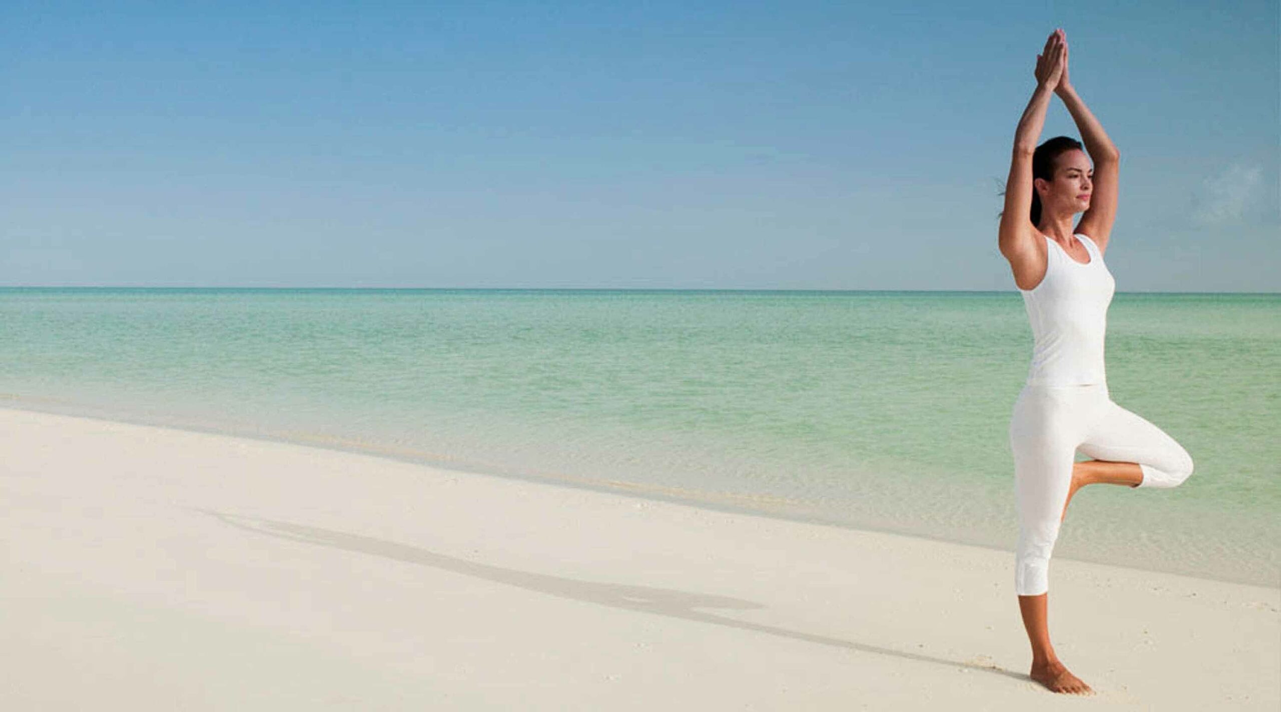 woman doing yoga on a sandy beach