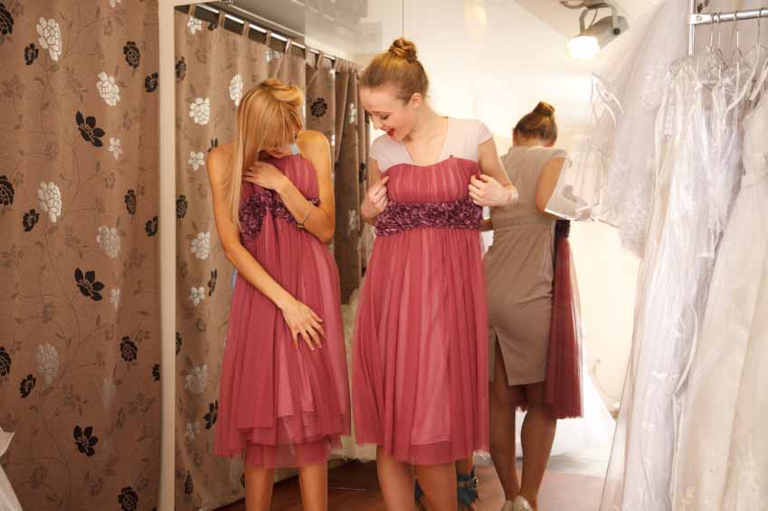 Two girlfriends - bridesmaids- having fun - looking for dresses for wedding