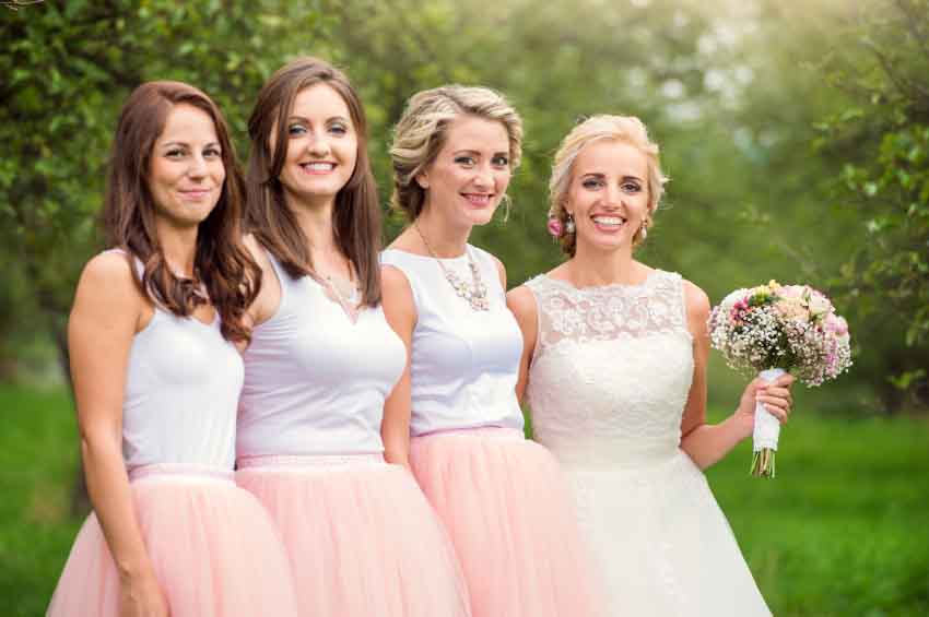 Beautiful young bride with her bridesmaids outside in nature
