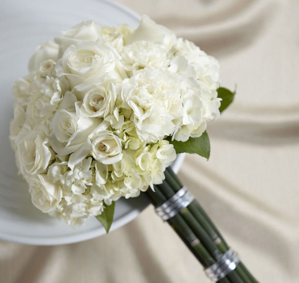 A bridal bouquet featuring white carnations mixed with roses and hydrangeas.