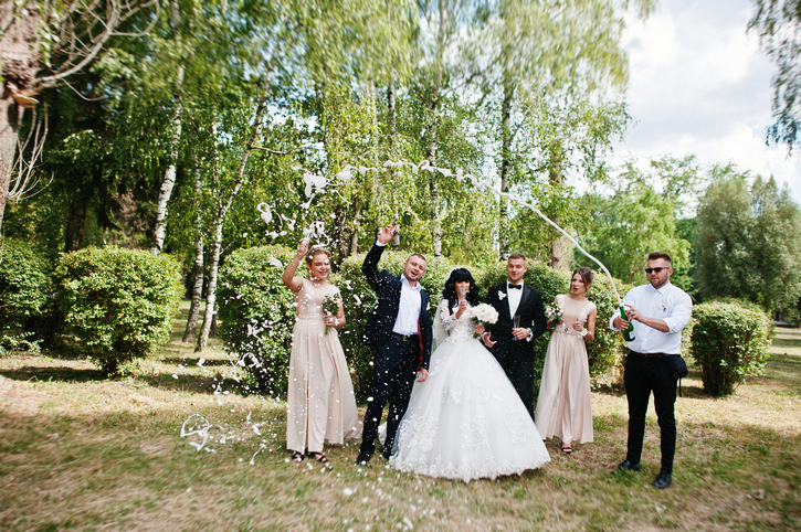 Stylish wedding couple, groomsman and bridesmaids with champagne explosion.