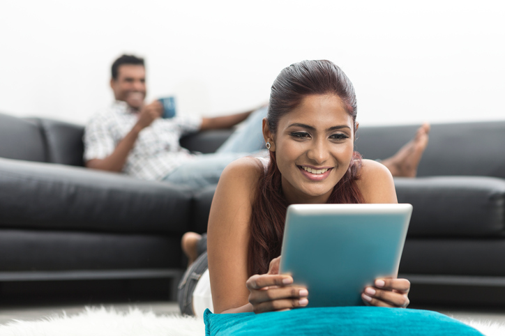 happy Indian woman using Digital Tablet at home