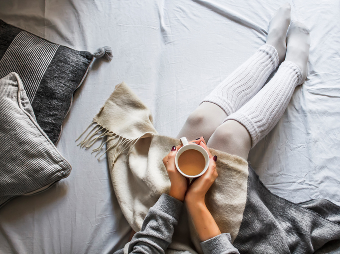 young woman on a bad holding a cup of coffee