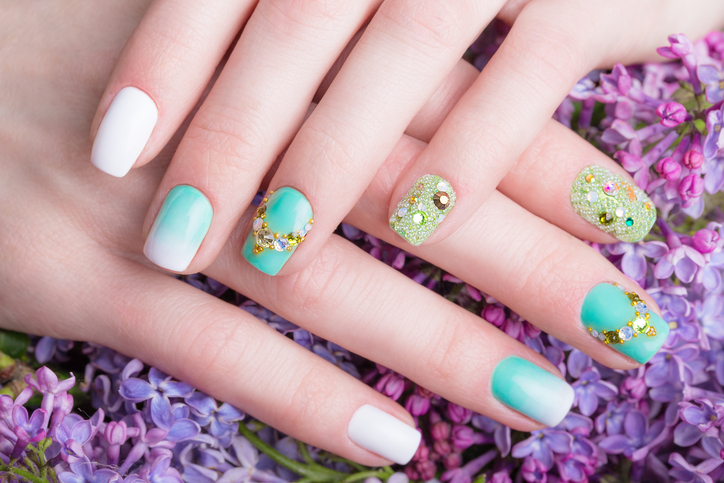 Beautiful turquoise manicure with crystals on female hand. Close-up.