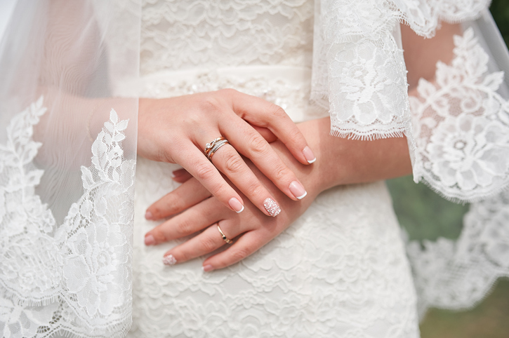 hands of the bride in a white dress with a manicure in wedding day.