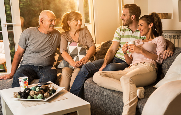 Happy senior people talking to young couple at home.