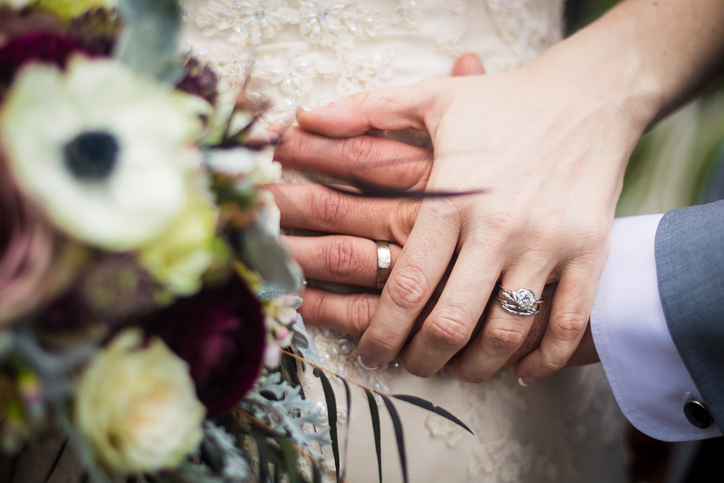 Image of a couple holding hands over the bride's dress with flowers