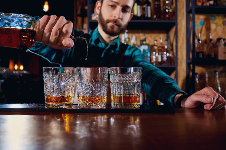 The barman pours alcohol into a glass. Close-up.