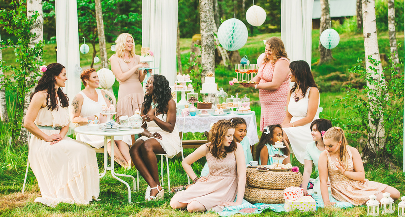 Eleven women having a garden party with dessert table