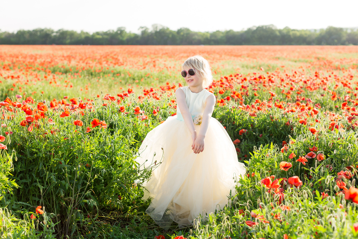 beautiful little girl model in a field of poppies, childhood, happiness, fashion, children, nature and summer flowers concept - smiling girlie in white fancy dress posing on poppy field, sunglasses