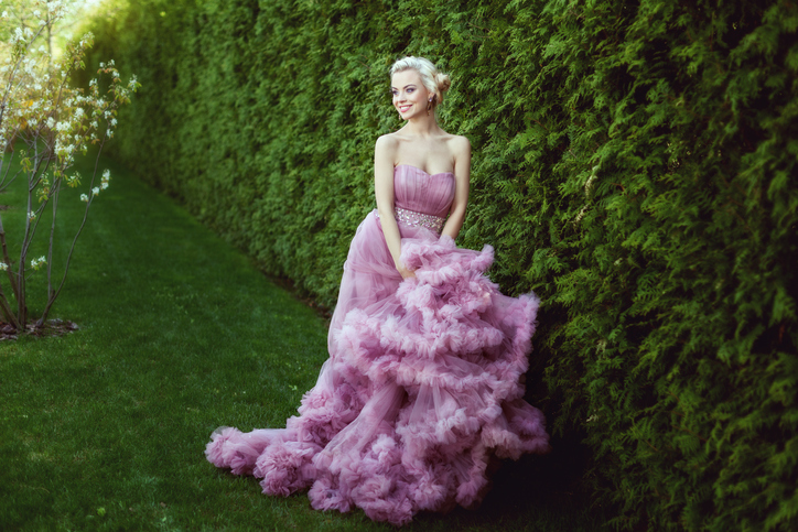 Happy woman in a lavender purple dress strolls through the park.