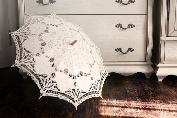 Openwork vintage umbrella against a dresser in style Provence