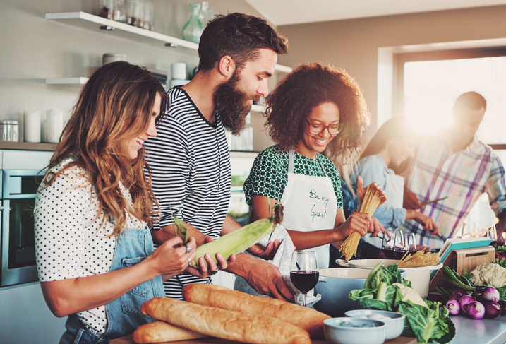 Friends preparing food at table in kitchen