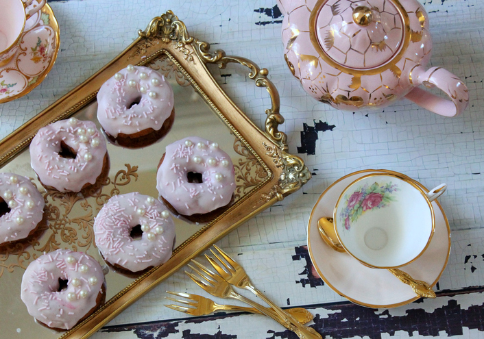 Iced donuts on a gold tray with vintage tea cup and saucer, teapot - afternoon tea party
