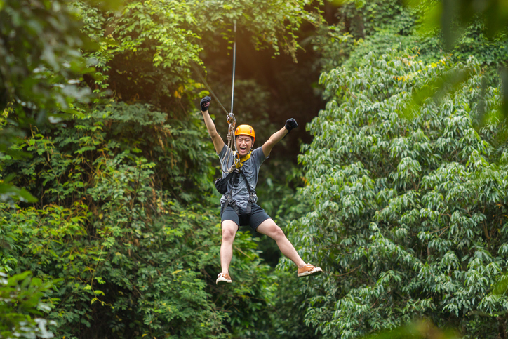 Freedom Man Tourist Wearing Casual Clothing On Zip Line Or Canopy Experience In Laos Rainforest, Asia