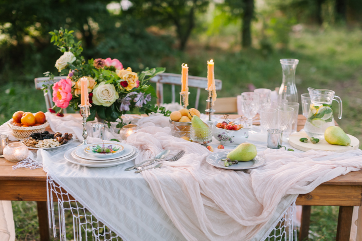 wedding, decoration, celebration, floral design, holidays concept - romantic table setting with white tablecloth, plates, crystal goblets, beautiful bouquet of roses and peonies and candels