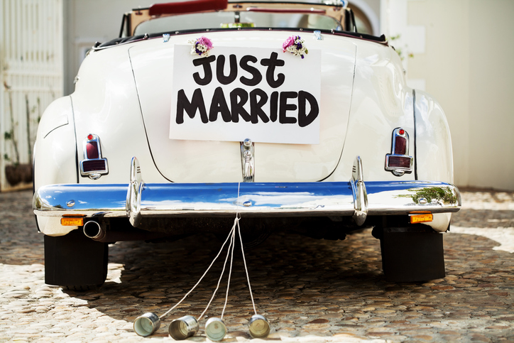 Just Married Sign And Cans Attached To Car's Trunk