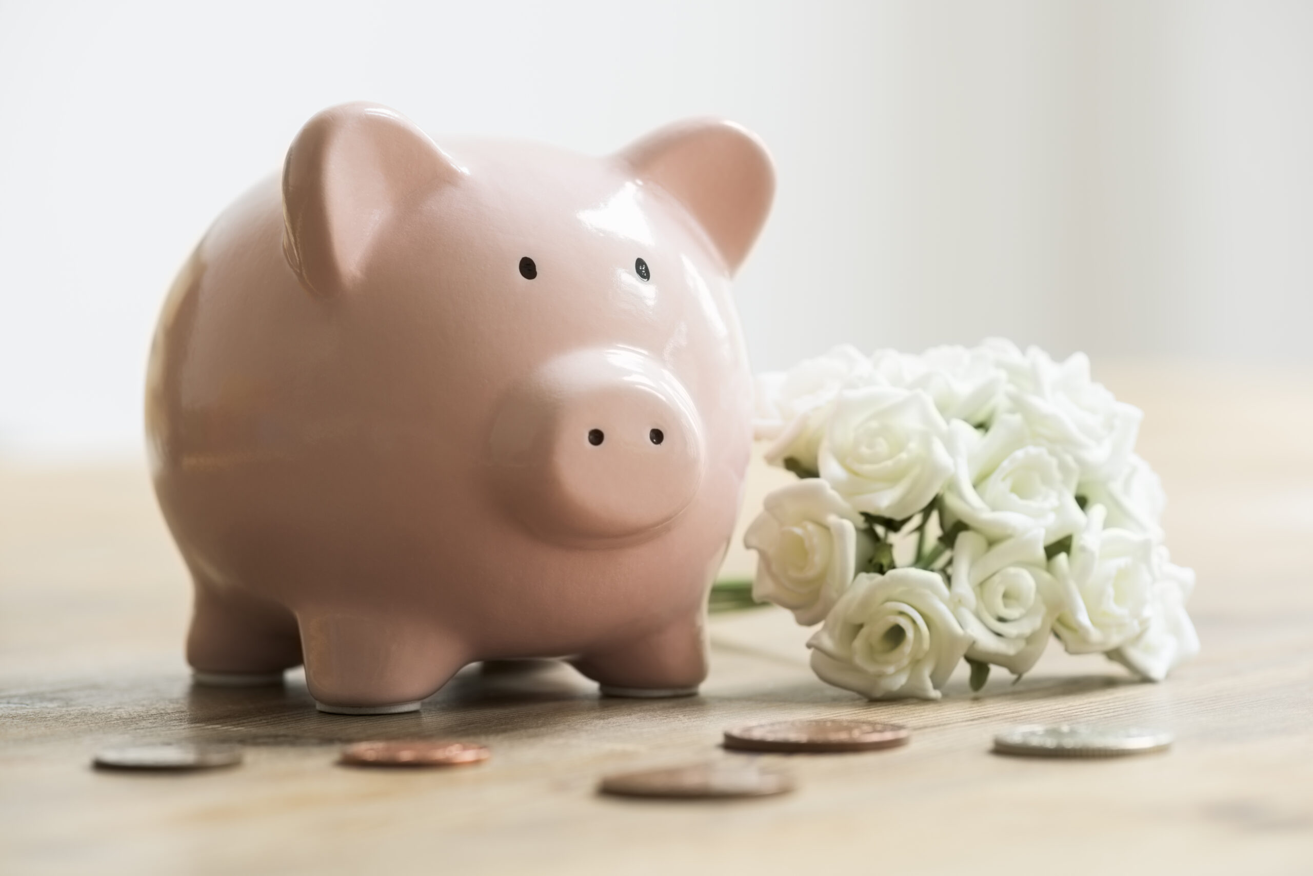 Wedding bouquet beside piggy bank and coins for saving