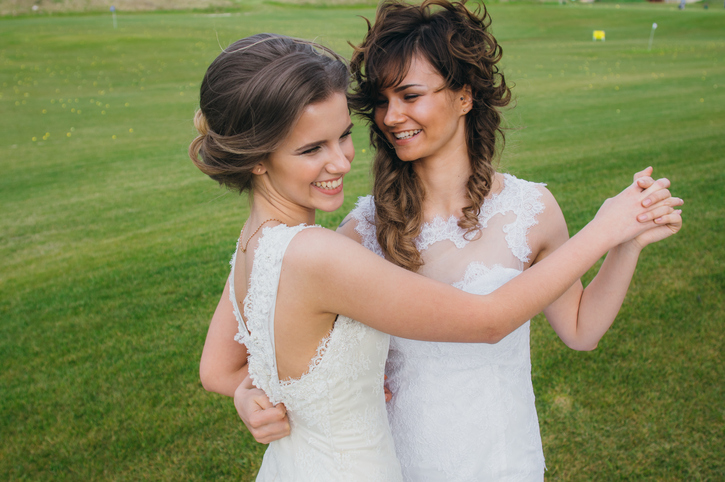 Two beautiful brides dancing on the green field