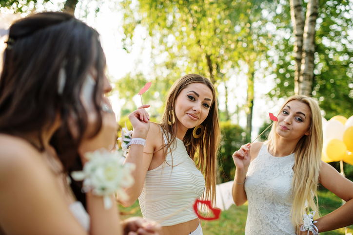 Girls wearing on white dresses having fun on hen party.