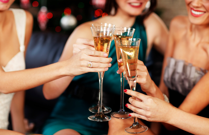 Girlfriends hold champagne glasses up while at christmas cocktail party