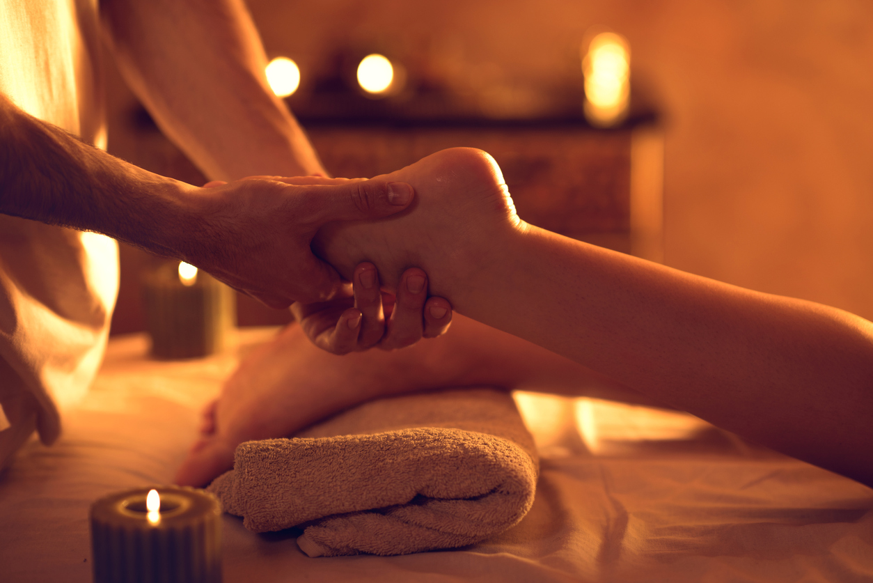 Unrecognizable massage therapist massaging woman's foot at spa.