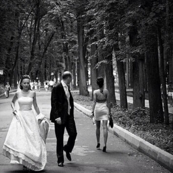 groom and bride in park girl walking past