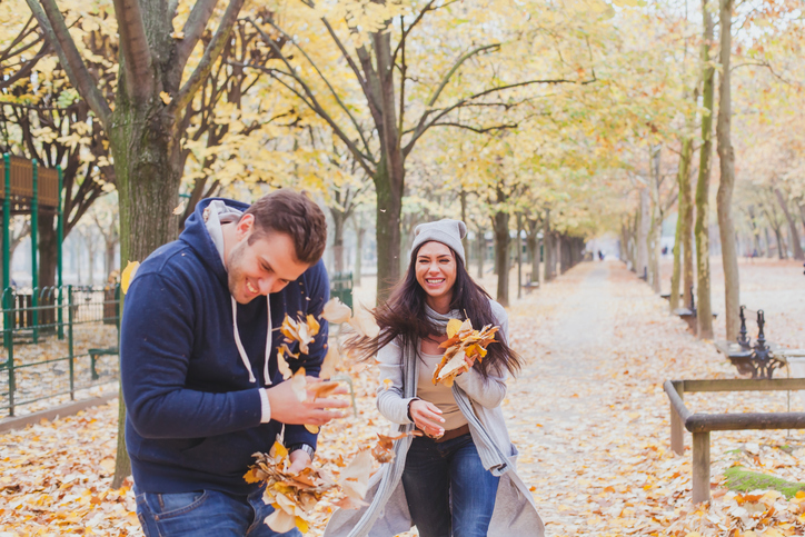 happy young couple playing and laughing together in autumn park