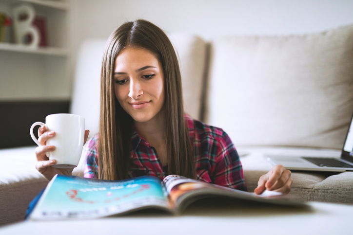 Young woman reading magazine at home