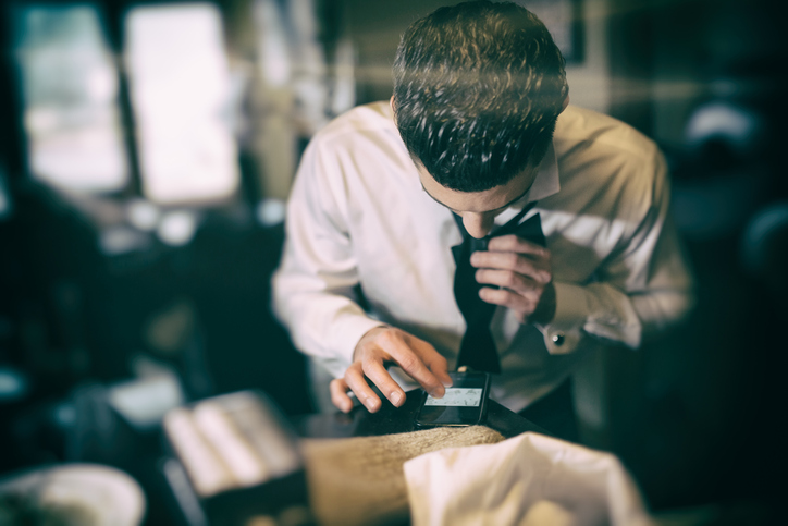 man uses smart phone to learn to tie bow tie