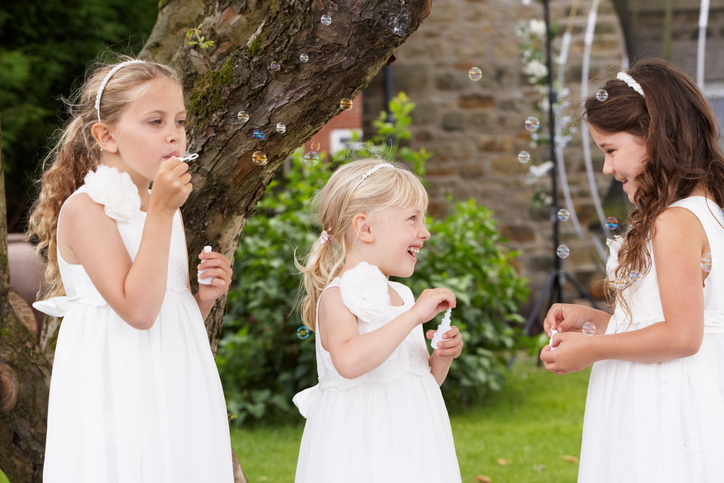 Group Of Bridesmaids Blowing Bubbles In Garden
