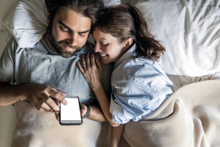Couple in Bed Using Smart Phone for Home Automation