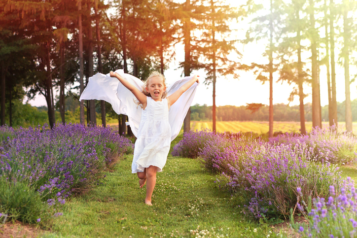 Girl running with a scarf in lavender field at sunset
