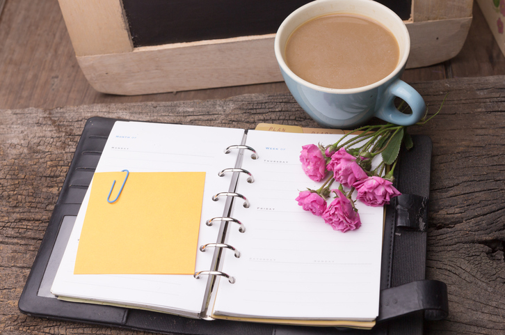 Weekend concept. Pink rose, mug with coffee, diary for note