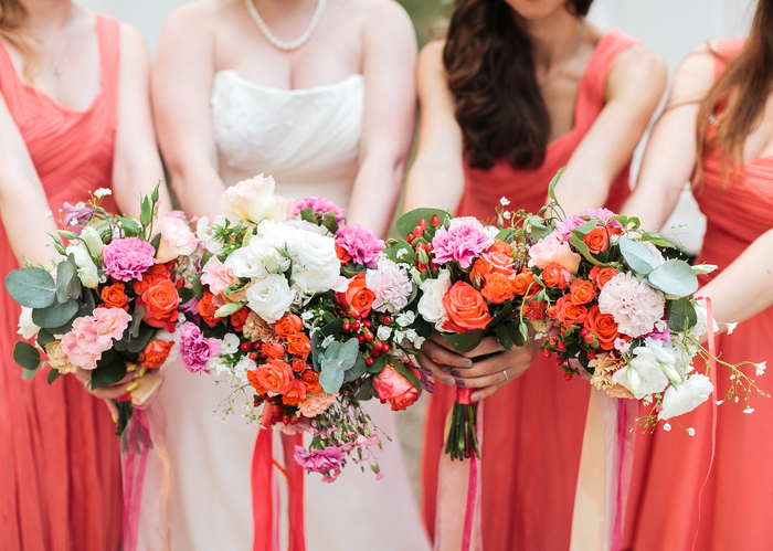 Bridesmaids and bride holds bouquets in hand.