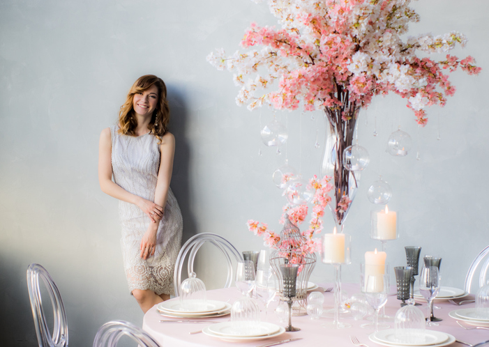 Smiling bride near the wall and wedding decorations