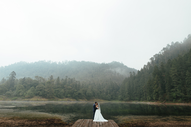 Romantic newlyweds kissing outdoors in foggy day