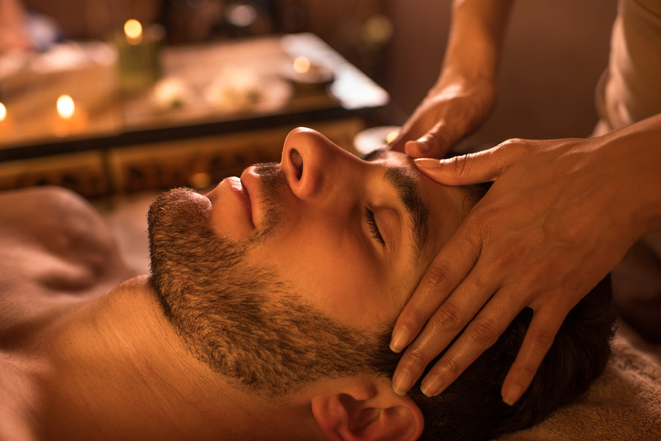 Close-up of a man receiving facial massage at the spa.