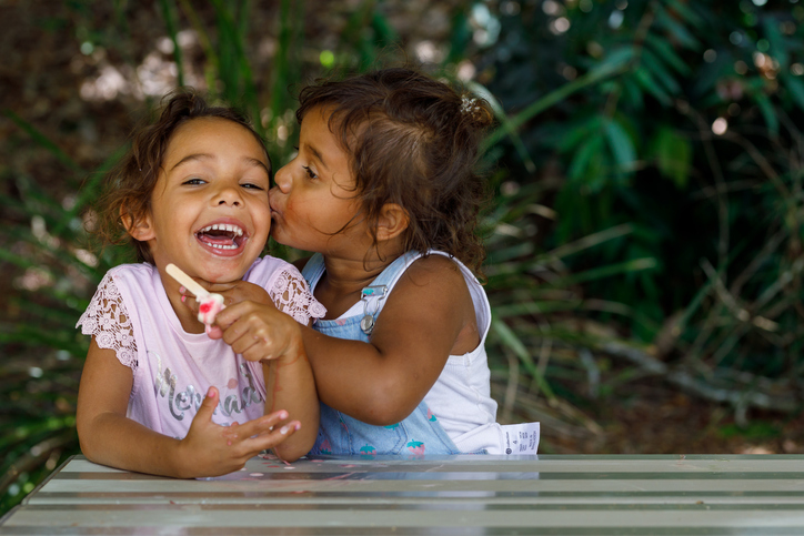 Two Young Australian Aboriginal Girls eating an Ice Cream And Laughing