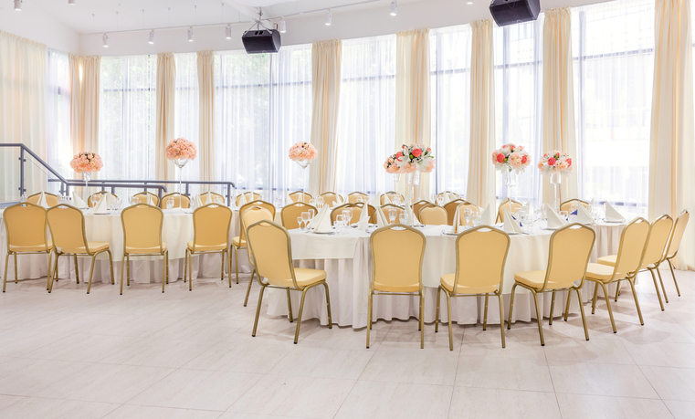 Beautifully decorated room with covered tables with flowers in the restaurant for the celebration of the wedding.